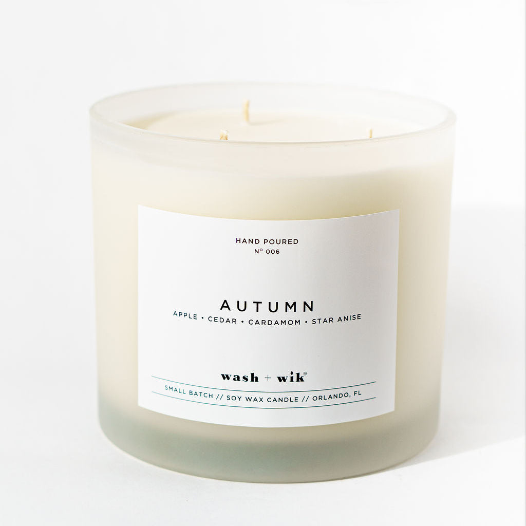 Candle with 'Autumn' label on a white background