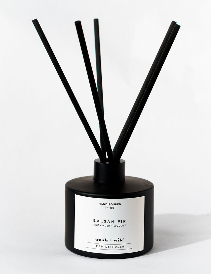 Black reed diffuser with a white label on a white background