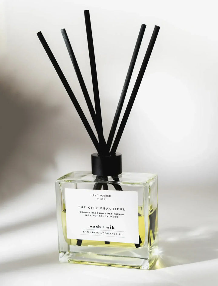 Reed diffuser with black sticks and a clear bottle on a white background