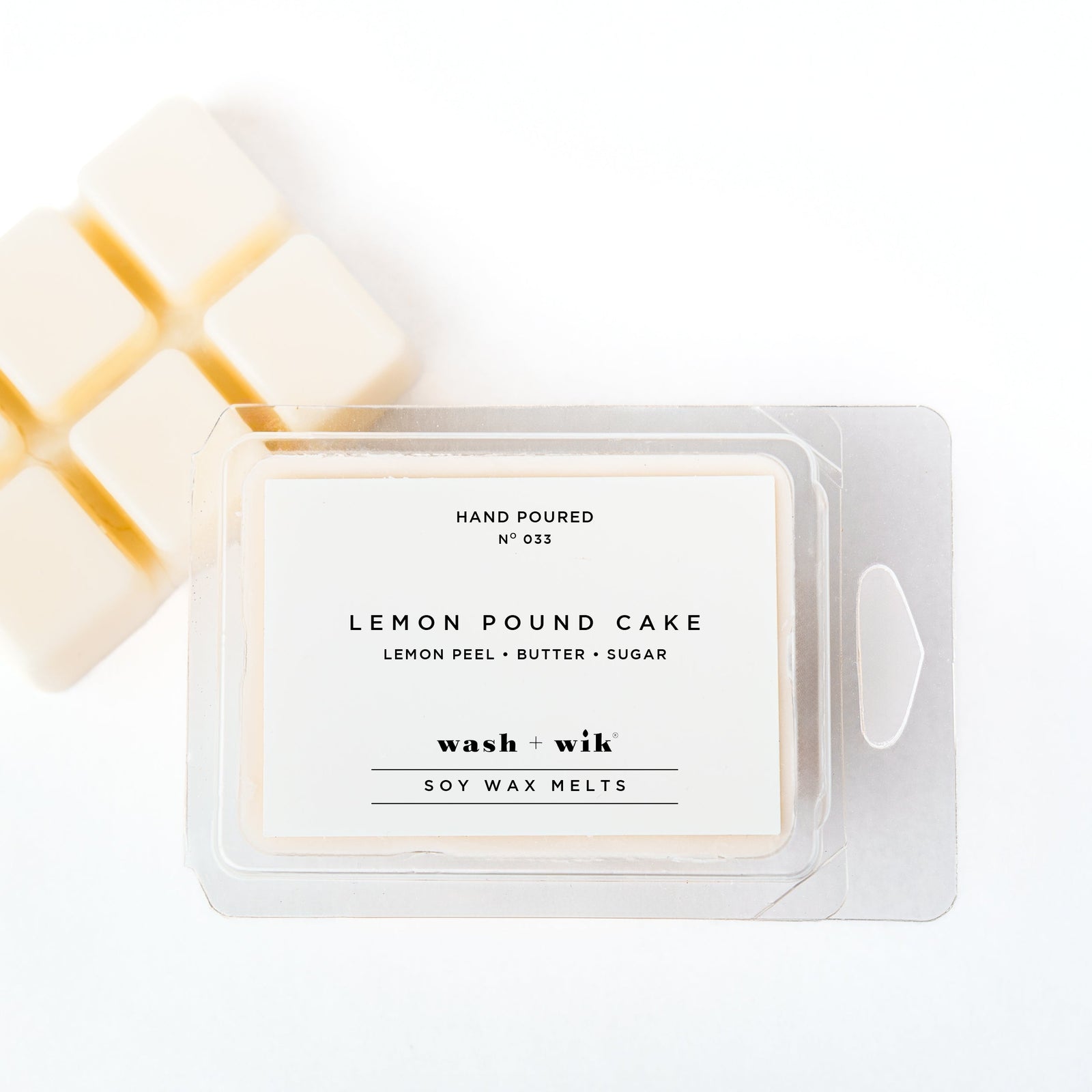 A clear plastic clamshell package of Wash + Wik soy wax melts on a white background, with several pale cream wax cubes partially visible behind it.