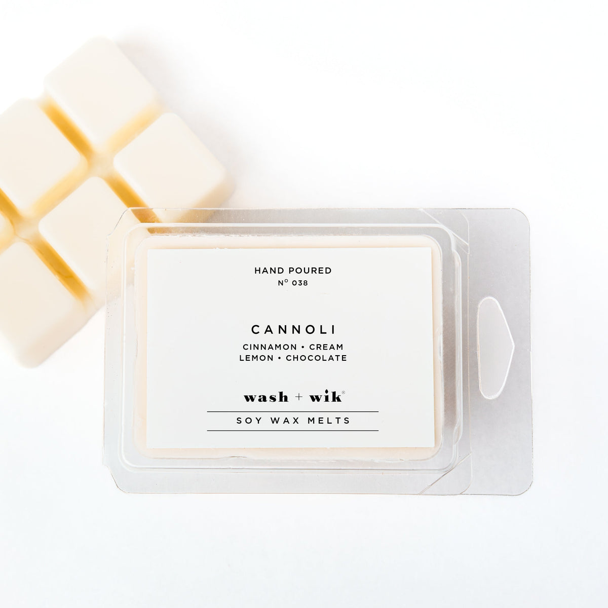 A clear plastic clamshell package of Wash + Wik Cannoli soy wax melts on a white background, with several pale cream wax cubes partially visible behind it.