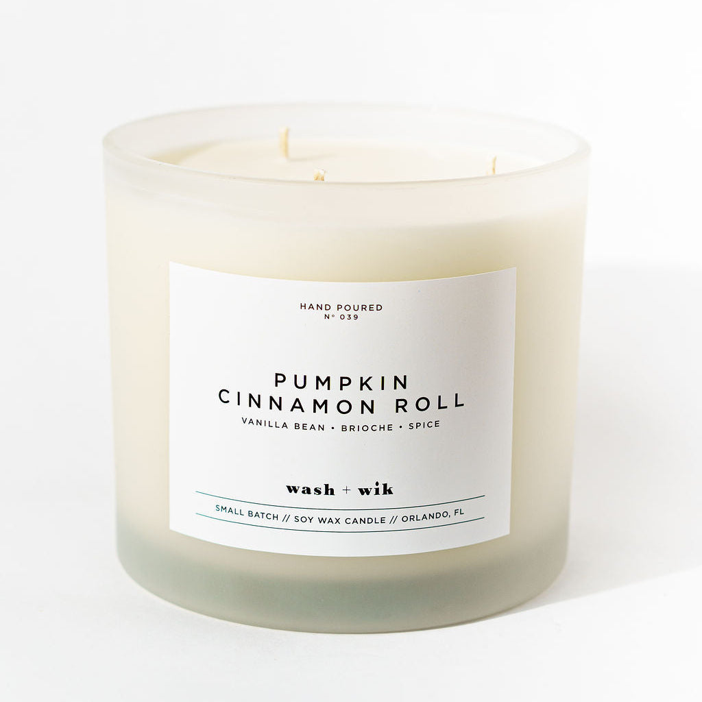 Candle labeled 'Pumpkin Cinnamon Roll' with a white label on a white background