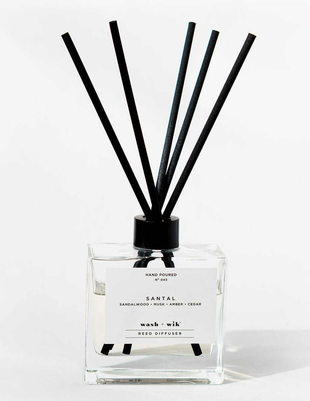 Reed diffuser with black sticks on a white background