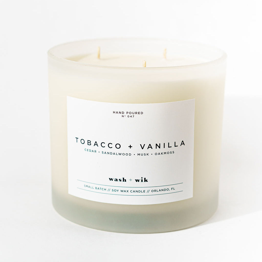 Candle with a label reading 'Tobacco + Vanilla' on a white background