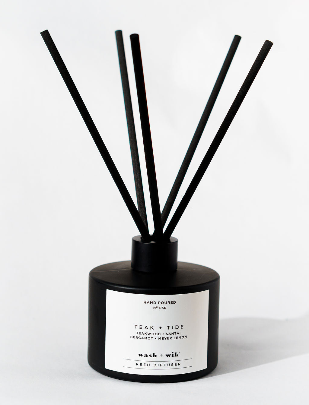 Black and white reed diffuser with sticks on a white background