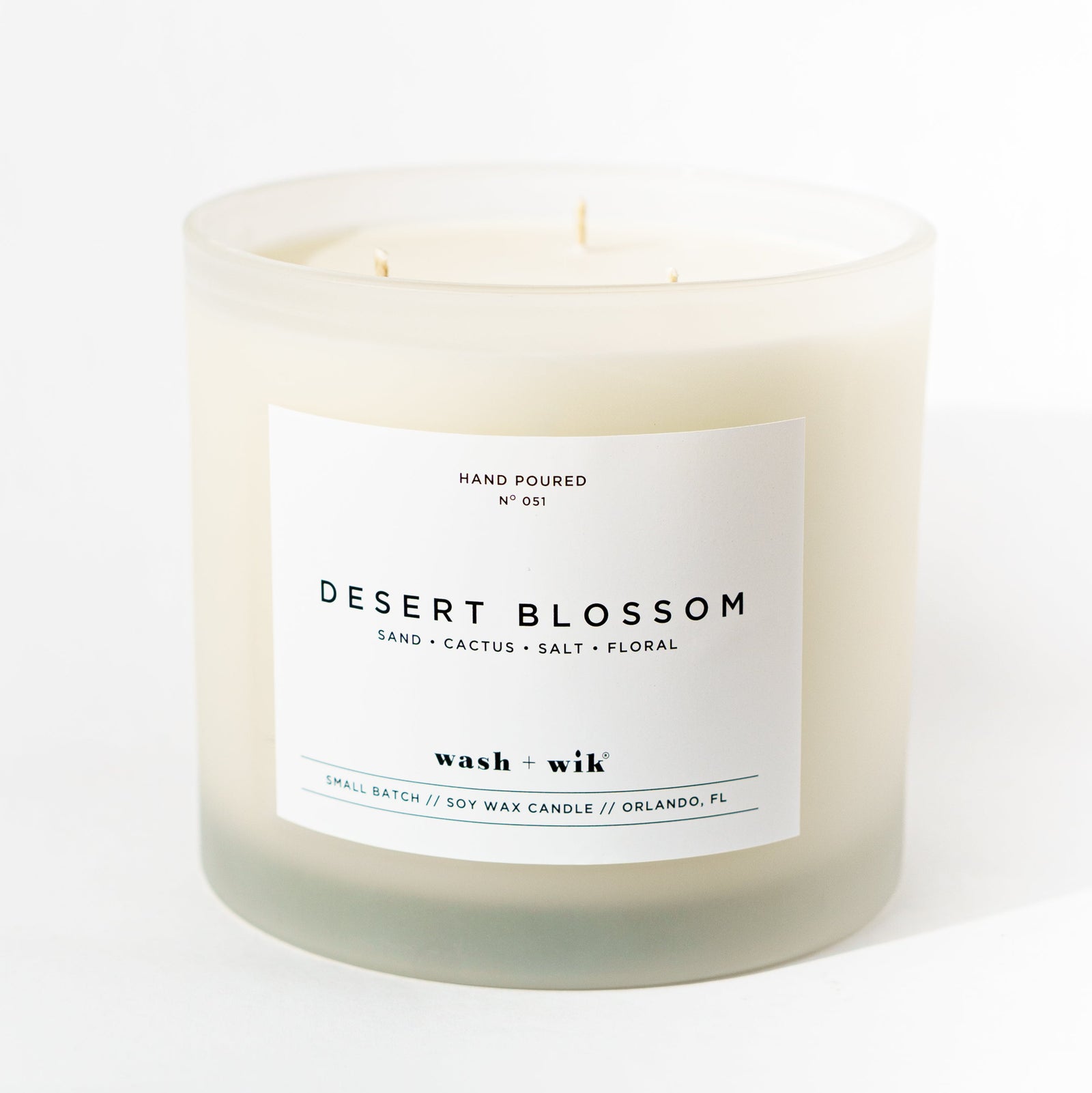 Candle labeled 'Desert Blossom' with a white label on a white background