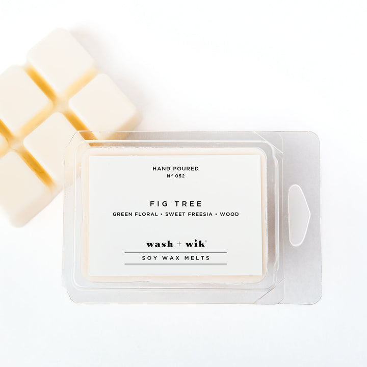 A clear plastic clamshell package of Wash + Wik soy wax melts on a white background, with several pale cream wax cubes partially visible behind it.