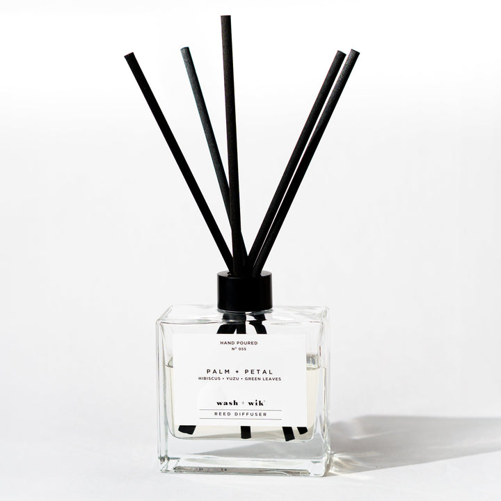 A clear glass reed diffuser bottle with a black cap 