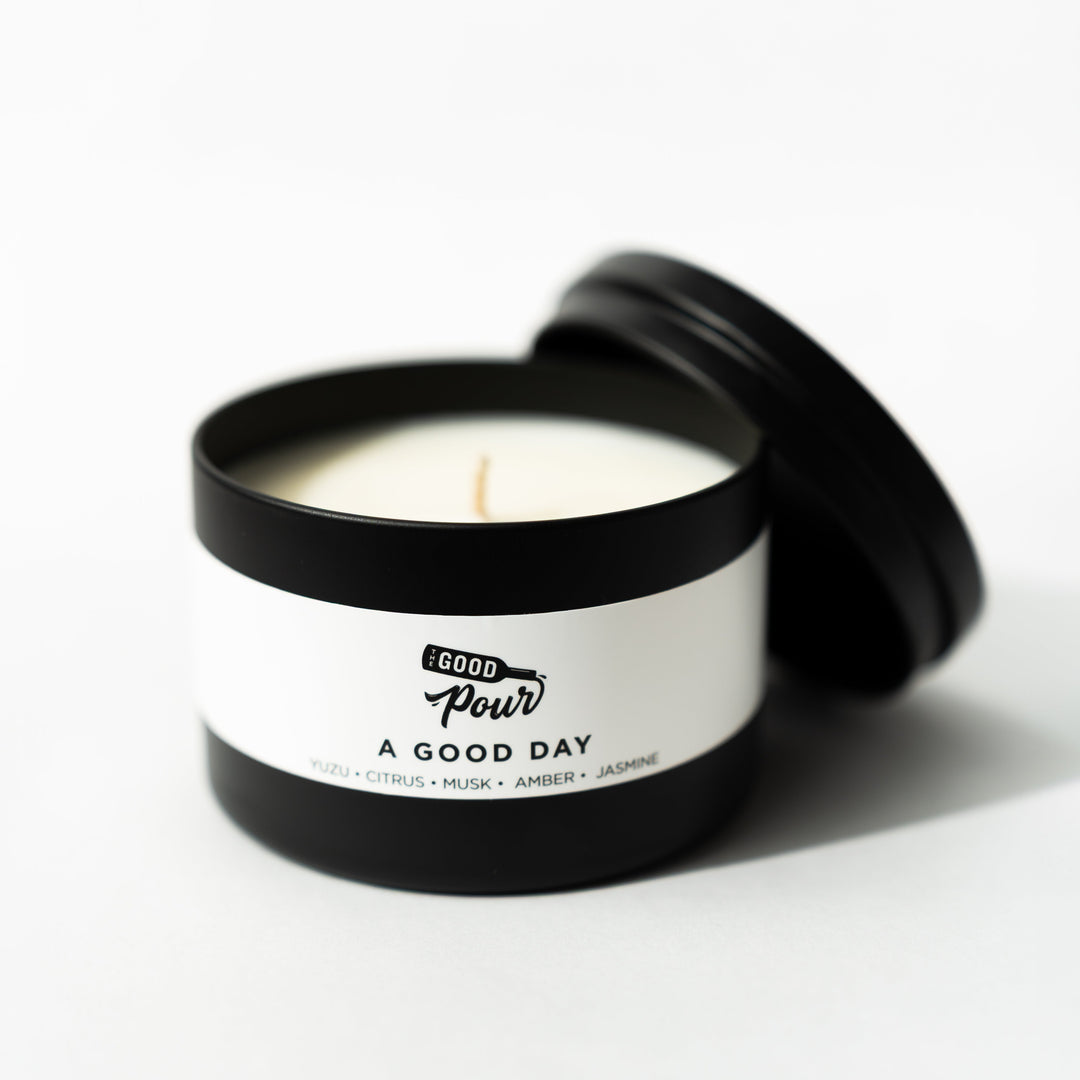 Candle in a black container with a white label on a white background