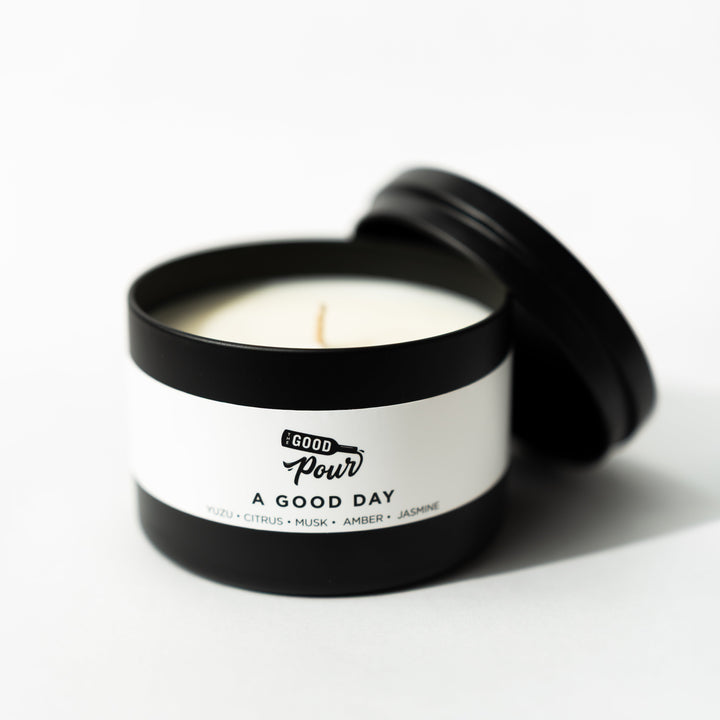Candle in a black container with a white label on a white background