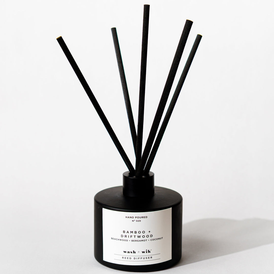 A black reed diffuser bottle with a black cap and five black reeds