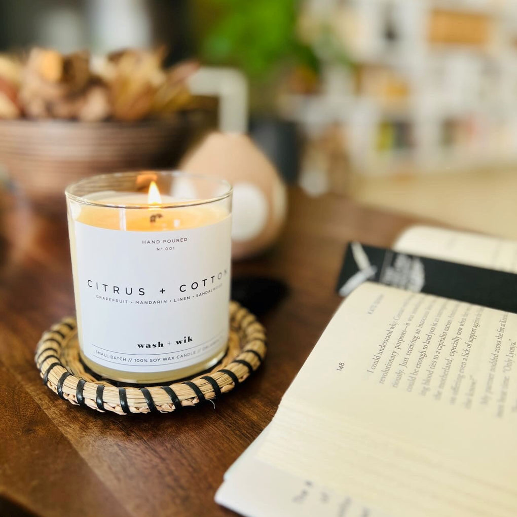 Candle labeled 'Citrus & Cotton' on a wooden surface with a blurred background