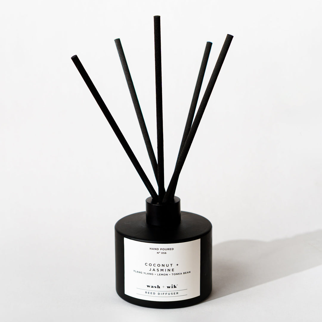 A black reed diffuser bottle with a black cap and five black reeds
