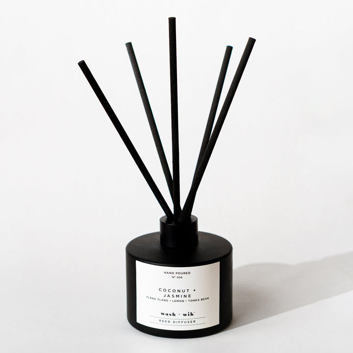 A black reed diffuser bottle with a black cap and five black reeds
