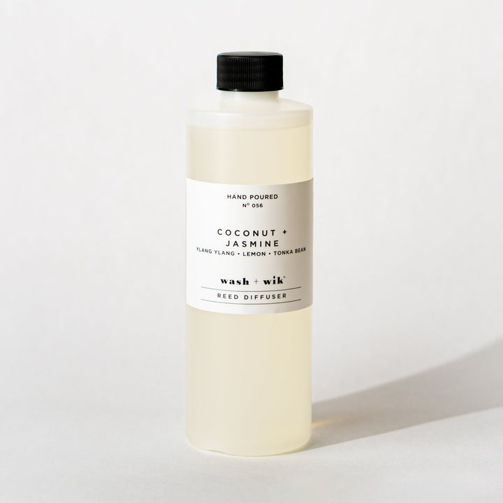 A bottle of Wash + Wik reed diffuser refill with a black cap and a minimalist white label, set against a clean white background with a soft shadow.