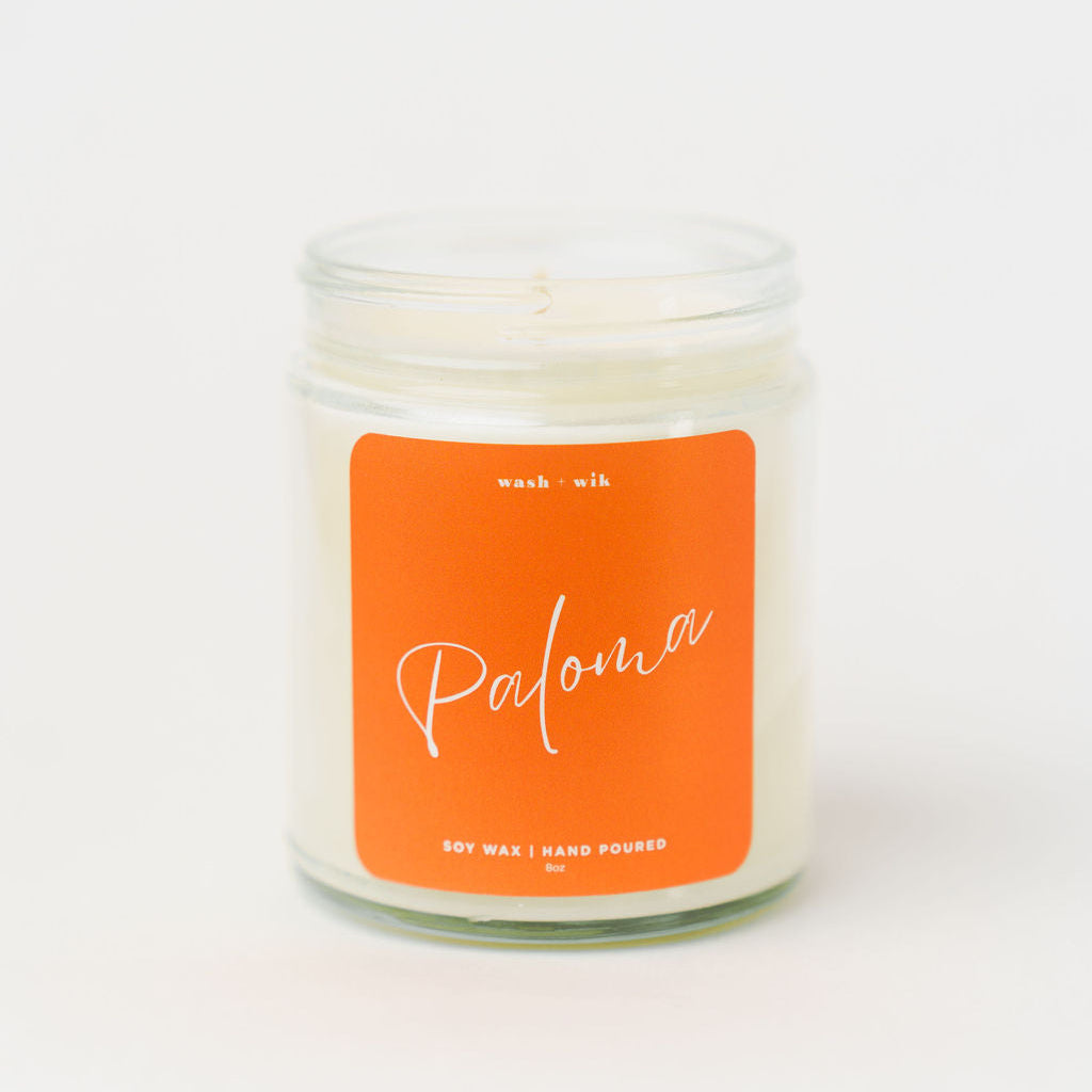 Candle in a glass jar with an orange label on a white background