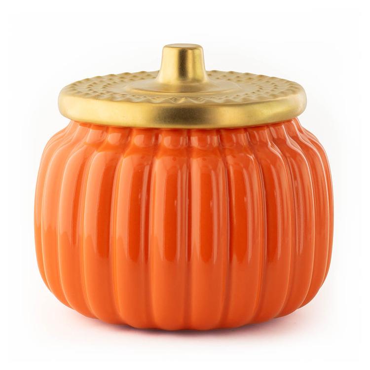 An orange pumpkin-shaped ceramic jar with a ribbed body and a metallic gold lid, shown on a plain white background.