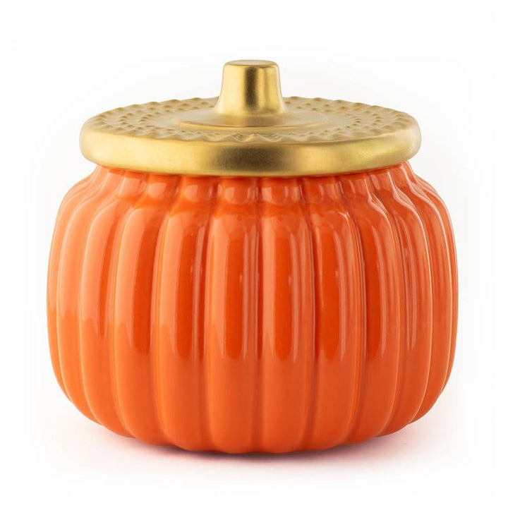 An orange pumpkin-shaped ceramic jar with a ribbed body and a metallic gold lid, shown on a plain white background.