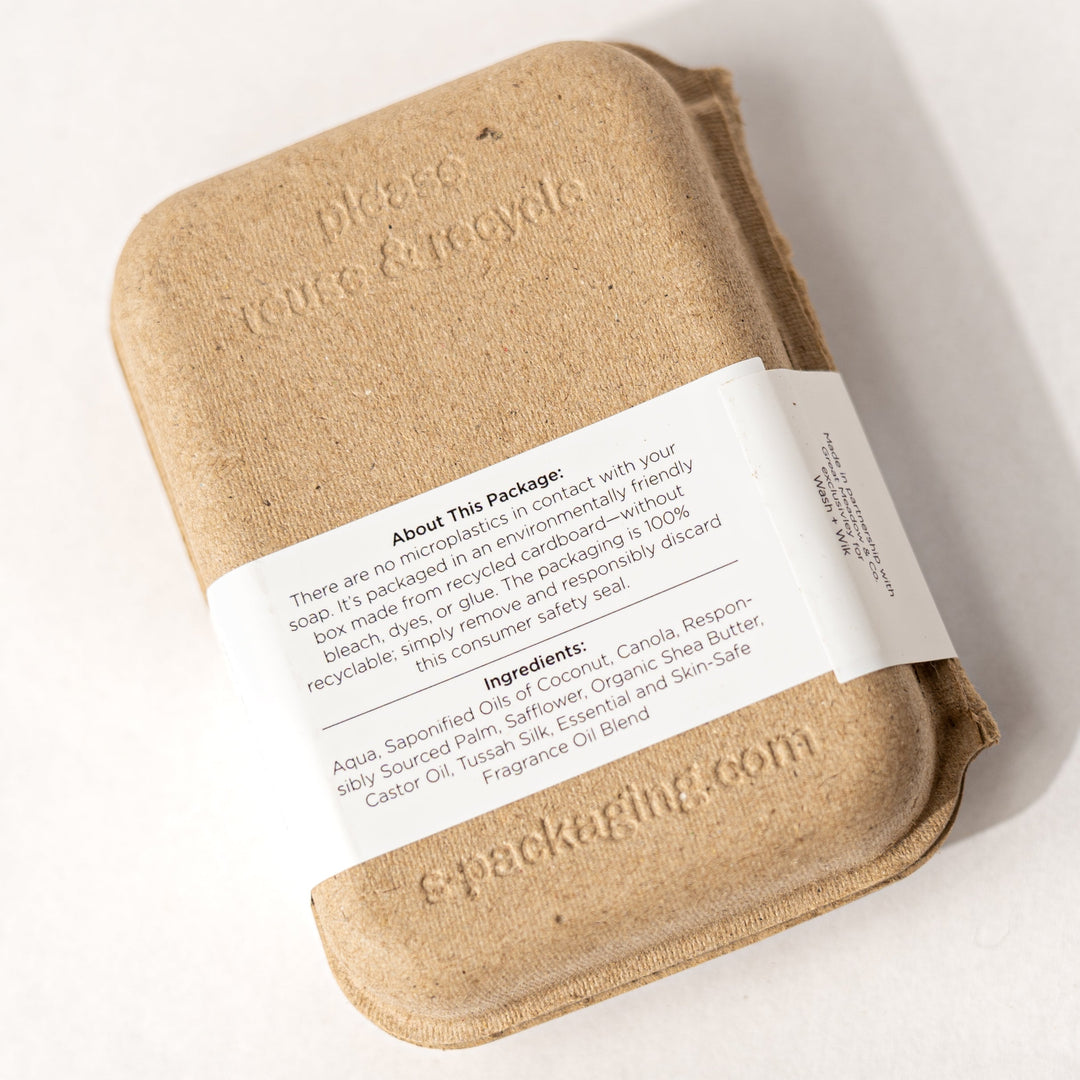 Bar of soap wrapped in brown paper with a label on a white background