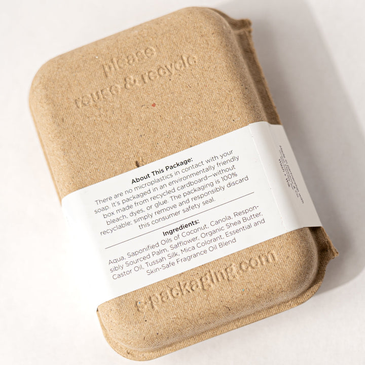 Bar of soap in a brown paper wrap with a label on a white background