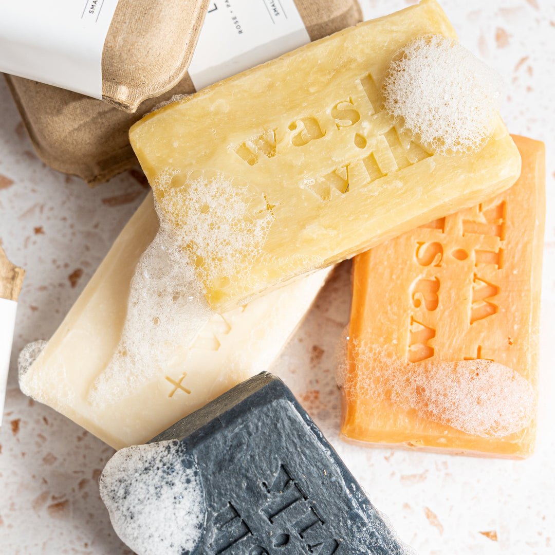 Three bars of soap in different colors on a textured surface