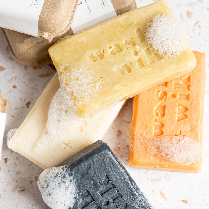 Three bars of soap in different colors on a textured surface