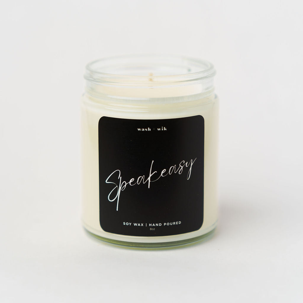 Candle in a glass jar with a black label on a white background