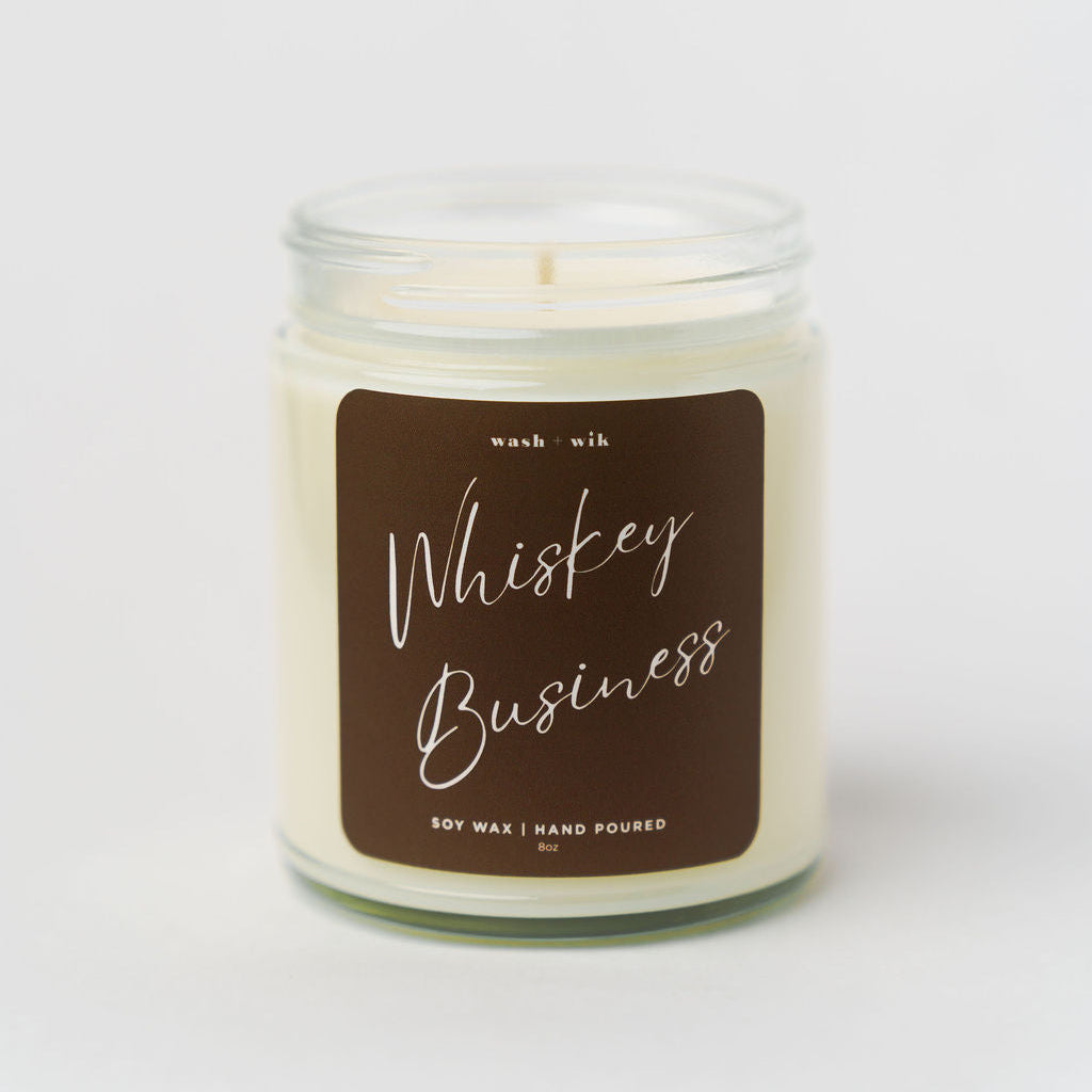 Candle in a glass jar with a brown label on a white background