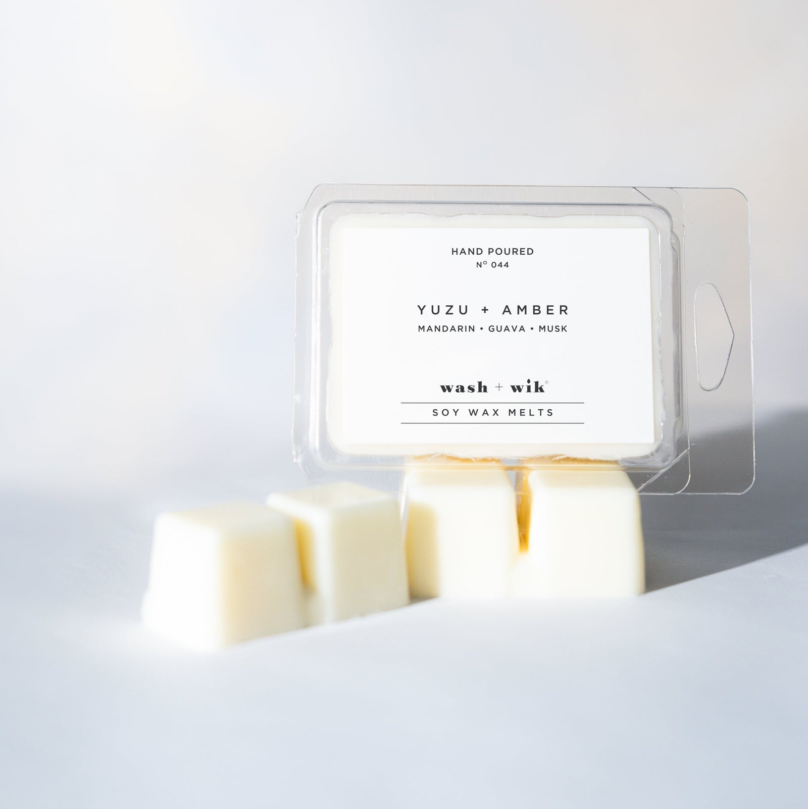Wax melt packaging labeled 'Yuzu + Amber' on a white background