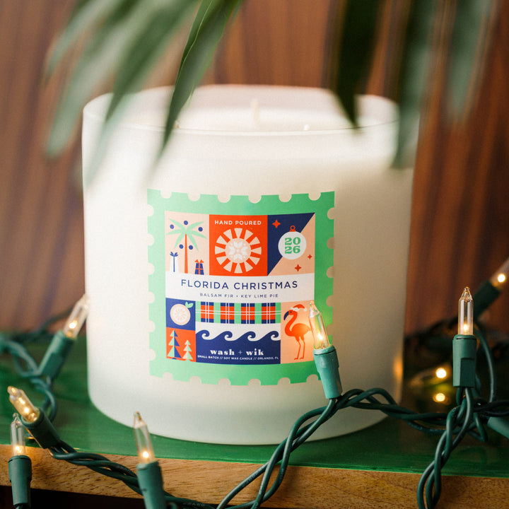 Large soy wax candle with festive background. Label is a stamp shape and says Florida Christmas