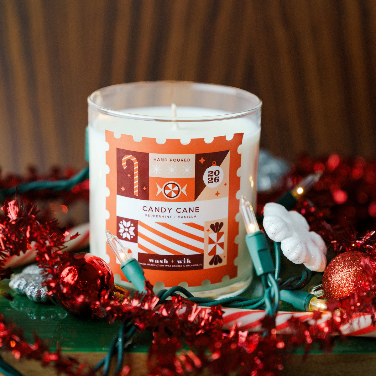 Soy wax candle with a festive background - label is a stamp shape and says Candy Cane with reds