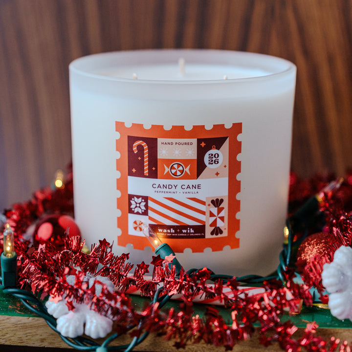 Large soy wax candle with a festive background - label is a stamp shape and says Candy Cane with reds