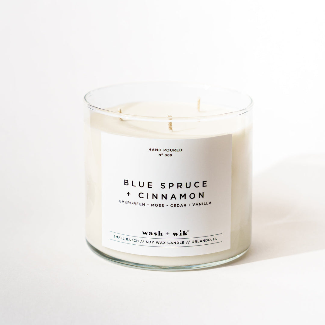A three-wick soy candle in a clear glass jar with a white label reading &