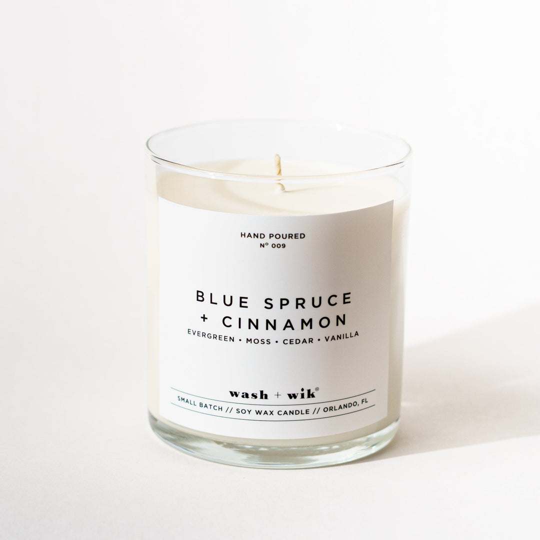 A single-wick soy candle in a clear glass jar with a white label reading &