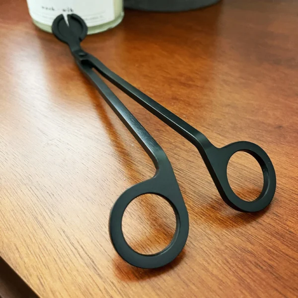 A pair of black scissors sitting on top of a wooden table.