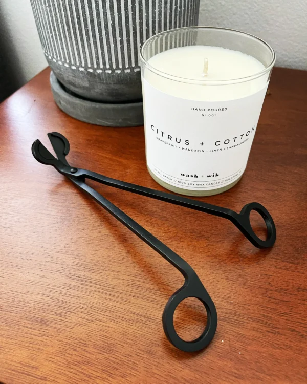 A candle and pair of scissors on top of a table.