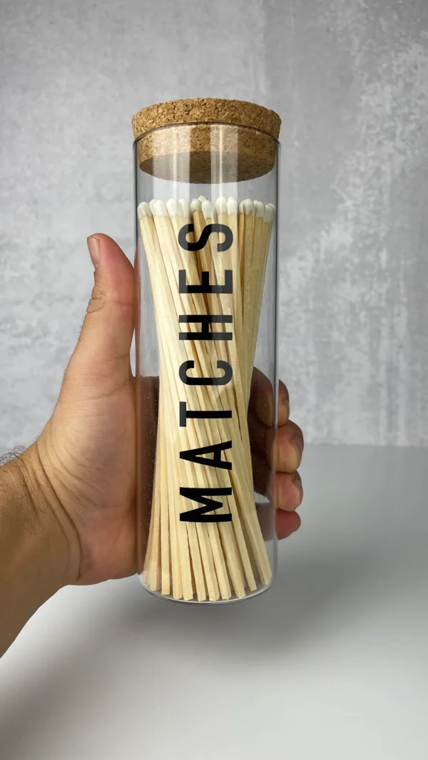 A person holding a glass container with matches in it.