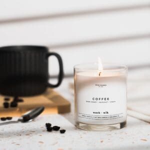 A candle sitting on top of a table next to a cup.