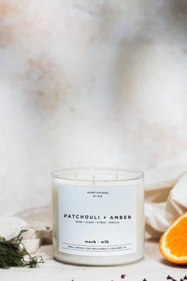 A candle sitting on top of a table next to an orange.