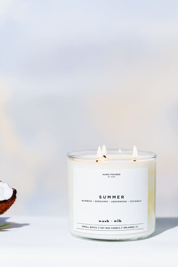 A candle sitting on top of a table next to a coconut.