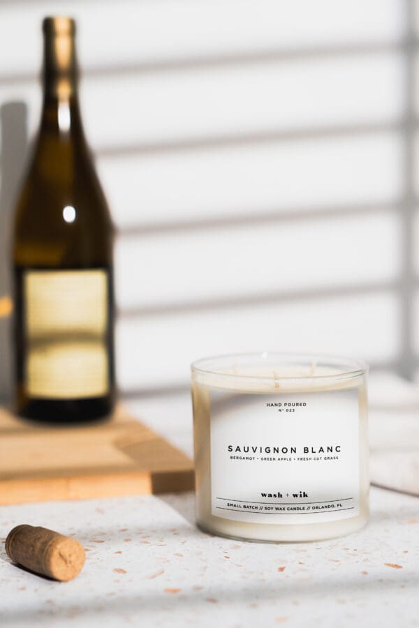 A candle sitting on top of a table next to a bottle.