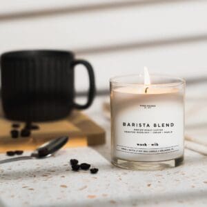 A candle sitting on top of a table next to coffee beans.