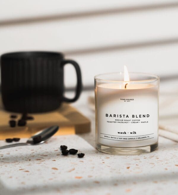 A candle sitting on top of a table next to coffee beans.