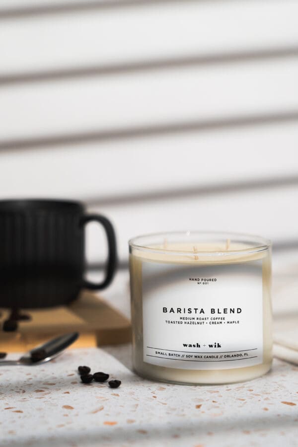 A candle sitting on top of a table next to a cup.