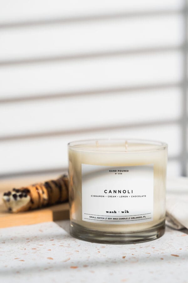 A candle sitting on top of a table next to a wooden spoon.