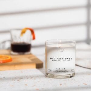 A candle sitting on top of a table next to a glass.