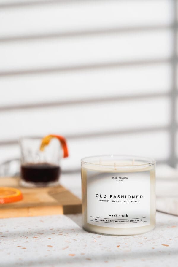 A candle sitting on top of a table next to a glass.