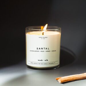 A candle is lit on the table in front of a black background.