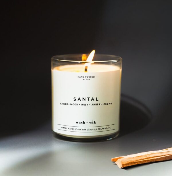 A candle is lit on the table in front of a black background.