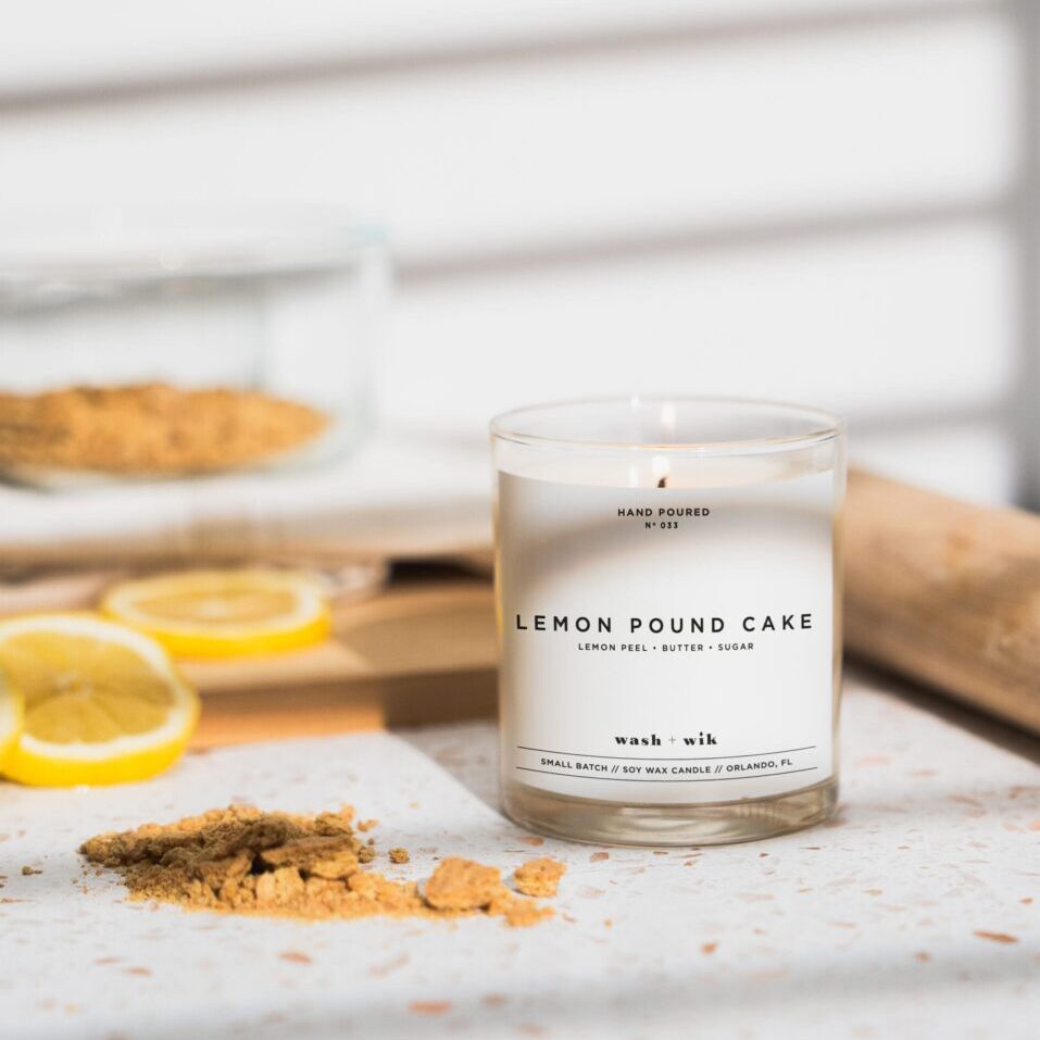 A candle sitting on top of a table next to lemons.